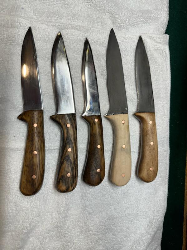 4 knives with wood handles in different shades of brown